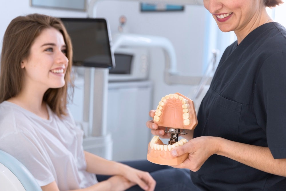 dentista mostrando dentes modelo para sorrindo paciente