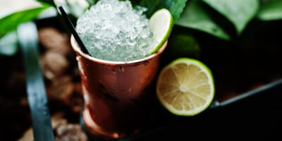 cocktail alcoolico com gelo e limao em bronze pode copo na mesa de bar