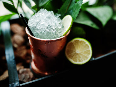 cocktail alcoolico com gelo e limao em bronze pode copo na mesa de bar