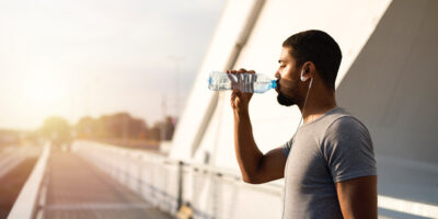 attractive athlete holding bottle of water and drinking before training.