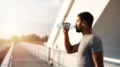 attractive athlete holding bottle of water and drinking before training.