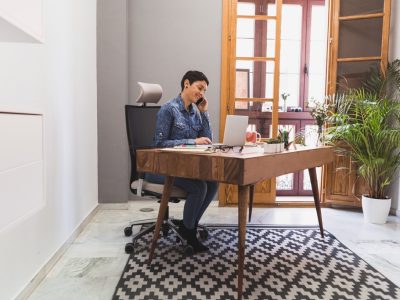 mulher de negocios que usa seu portatil e falando no telefone