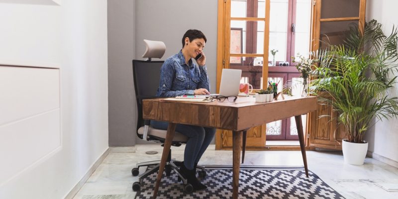 mulher de negocios que usa seu portatil e falando no telefone